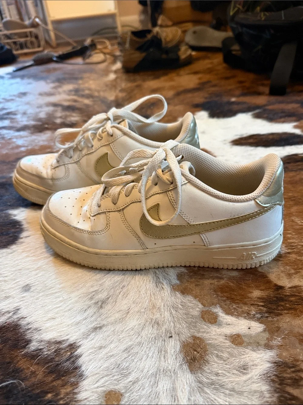 Nike low top Air Force ones. All white with gold swoosh.
